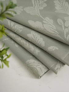 Close-up of sage green jacquard fabric with leaf texture and precise stitching