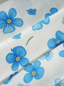 Detail of blue gradient floral print on white mesh fabric with hollow lace edging
