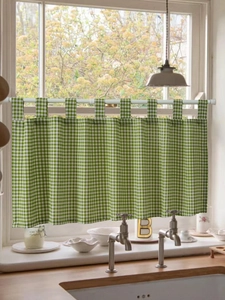 Detail of green checkered tab top cafe curtain hanging on a rod in a bright window