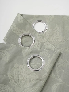 Close-up of sage green jacquard curtain with damask patterns and silver metal grommets