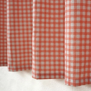 Detail of orange plaid cotton linen cafe curtain fabric texture with neat hemmed edges