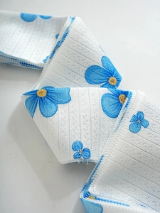 Detailed macro view of white fabric tape featuring delicate blue floral patterns and fine stitching