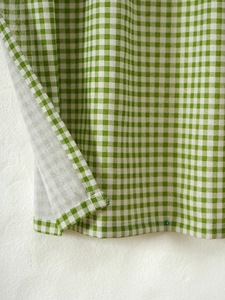Close-up of green and white gingham fabric showing detailed stitching and cotton texture