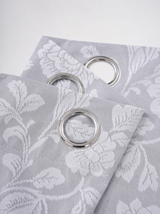 Detail of grey jacquard blackout curtain with white floral patterns and silver grommets