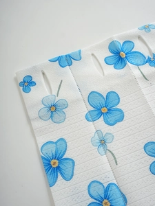 Detail of floral printed folding curtain fabric with blue flowers and hanging holes