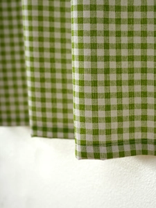 Detail of green and white plaid cotton-linen cafe curtain with stitched hem edge