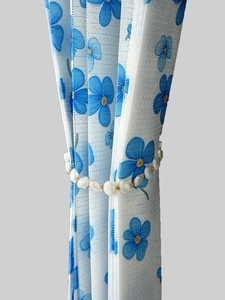Close-up of shell-shaped beads and gold accents on a floral curtain tieback