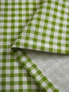 Detailed close-up of green and white plaid cotton linen fabric with fine hemmed edges