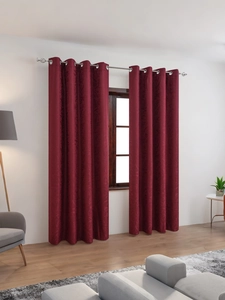 Detail of burgundy blackout curtains with floral jacquard pattern and silver metal grommets