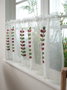 Detail of white sheer cafe curtain with red and green leaf embroidery and pom-pom trim