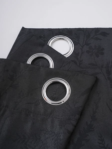 Detail of black blackout curtain fabric with floral jacquard and silver metal grommets
