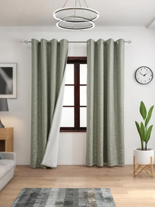 Detail of green floral blackout curtain with silver metal grommets and thick fabric texture