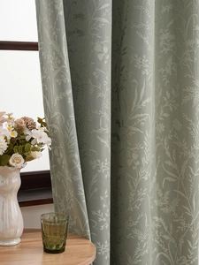 Detail of sage green floral jacquard curtain with thick blackout fabric and elegant folds