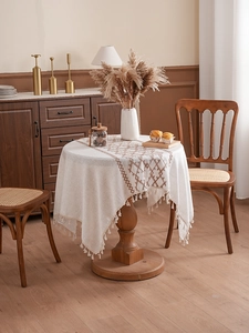 Close-up of thick linen tablecloth featuring geometric embroidery and delicate tassels