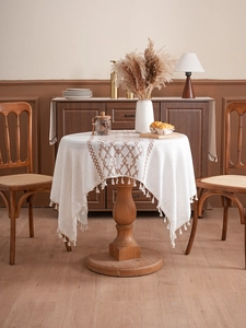 Detail of embroidered linen tablecloth featuring geometric patterns and fringe edges