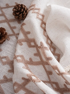 Close-up of thick linen tablecloth with brown geometric diamond embroidery texture