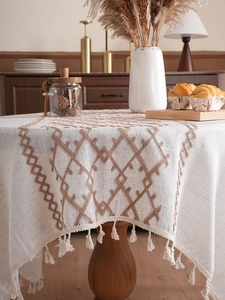 Detail of linen tablecloth with brown diamond embroidery and handmade tassel edges