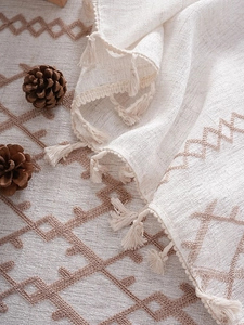 Macro detail of thick linen tablecloth with geometric embroidery and handmade fringe tassels