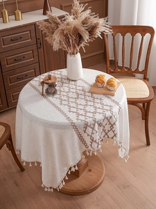Close-up of cream linen tablecloth with brown diamond weave patterns and tassels