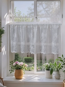 Detailed view of white lace cafe curtain with palm tree embroidery and scalloped edges