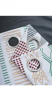 Close-up of silver metal grommets and geometric patterns on white blackout curtain fabric