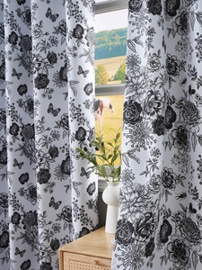 Detail of white blackout curtains featuring black hand-drawn floral and butterfly prints
