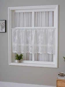 Detail of white lace cafe curtain featuring tropical palm tree jacquard and wavy hem