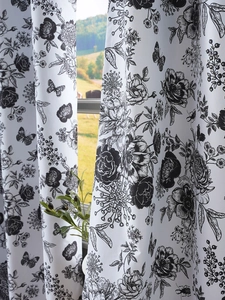 Detail of white blackout curtain featuring black floral sketches and butterfly prints