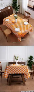 Close-up of orange and white checkerboard tablecloth with natural drape and woven texture