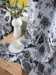 Detail of white blackout curtain featuring black floral and butterfly sketch patterns