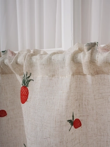 Detail of linen cafe curtain featuring fruit embroidery and rustic ruffled edges