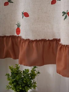 Detailed macro view of linen curtain with red pineapple embroidery and ruffle hem