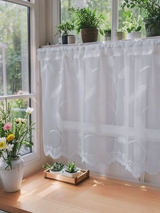 Detail of white lace cafe curtain with wheat embroidery and wavy scalloped edges