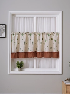 Detail of linen cafe curtain featuring green cactus embroidery and brown ruffled edges