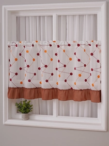 Detail of white cafe curtain featuring geometric orange embroidery and ruffled orange hem