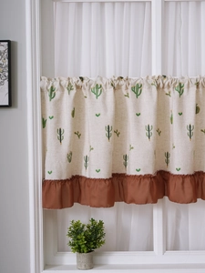 Detail of linen cafe curtain with cactus embroidery and dark brown ruffled hem