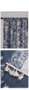 Détail de rideau bleu à motif floral blanc avec pompons et franges décoratives