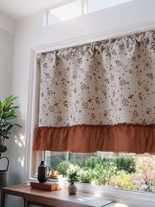 Detail of floral dragonfly cafe curtain with orange ruffled edge on a sunny window