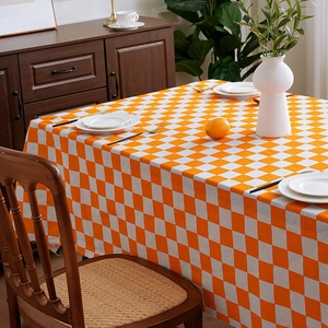 Nordic orange and white checkered tablecloth on wooden table with minimalist home decor