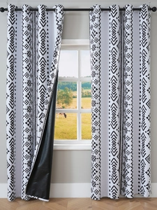 Close-up of black and white geometric curtains with black blackout lining and metal grommets