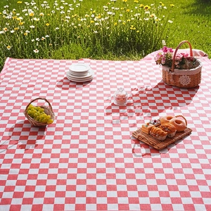 Outdoor red and white checkered picnic mat spread on lush grass for garden leisure