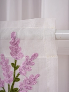 Detail of white cafe curtain featuring lavender embroidery and semi-transparent fabric texture