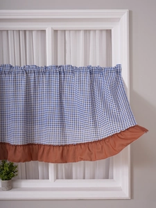 Detail of blue and white checkered kitchen curtain with brown ruffle trim in rustic style