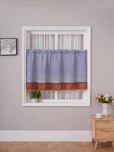 Detail of blue gingham checkered curtain with brown ruffle trim for kitchen cabinets