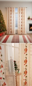Detail of beige lace Christmas curtains featuring embroidered red bells and festive lights