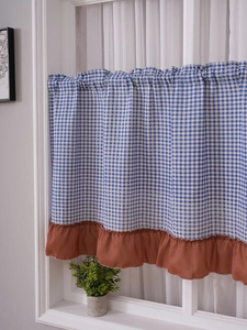 Detail of blue gingham curtain with brown ruffle trim in a cozy kitchen setting