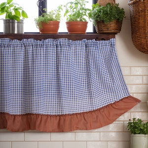Blue plaid checkered cabinet curtain with rust red ruffle trim in a rustic kitchen setting