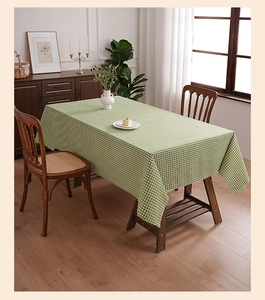 Detail of green and white gingham tablecloth with linen texture on rectangular dining table