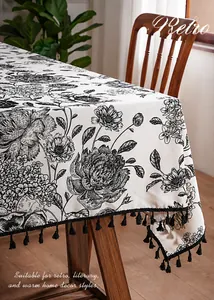Detail of vintage floral linen tablecloth with retro hand-drawn pattern and black tassel trim