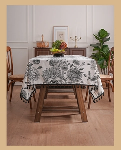Detailed close-up of vintage floral linen tablecloth with elegant black tassels and fringe